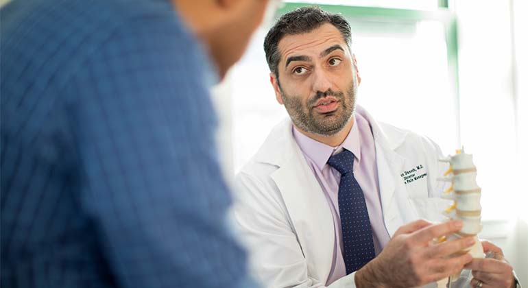 Doctor showing man a model spine